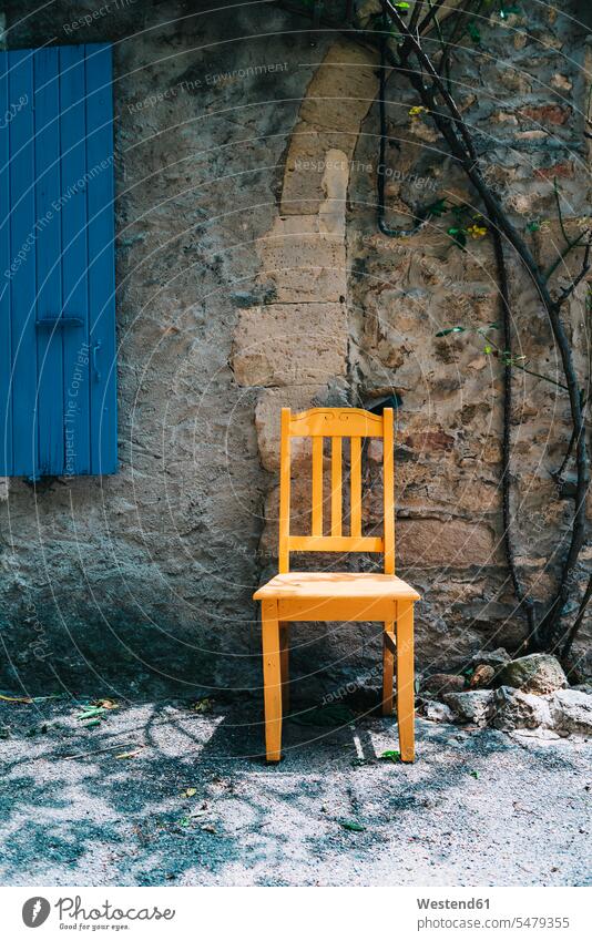 France, Grignan, yellow wooden chair in front of an old house nobody empty emptiness house front single object 1 one wooden chairs shutter window shutters