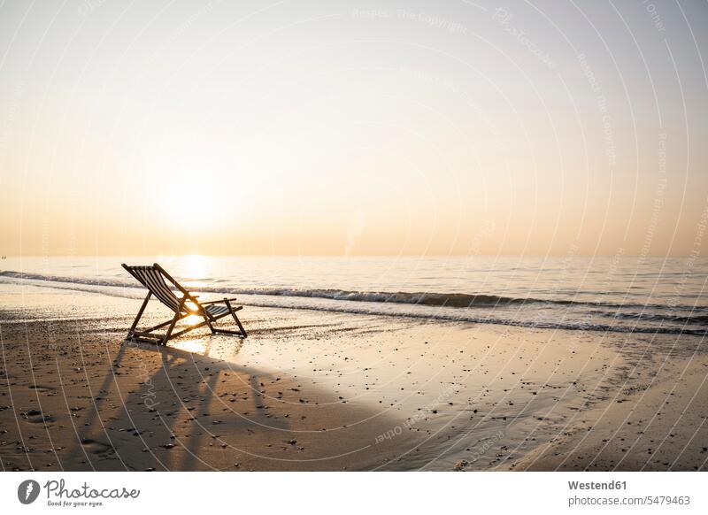 Empty folding chair on shore at beach against clear sky during sunset color image colour image Netherlands Holland The Netherlands Nederland outdoors