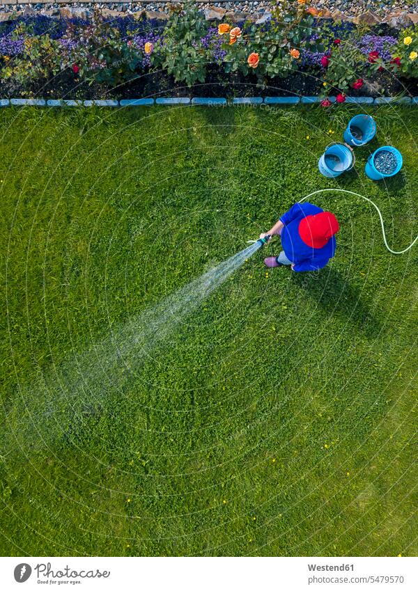 Aerial view of adult woman watering grass in backyard outdoors location shots outdoor shot outdoor shots day daylight shot daylight shots day shots daytime