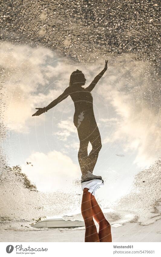 Reflection of woman with arms outstretched on puddle during vacation color image colour image outdoors location shots outdoor shot outdoor shots day