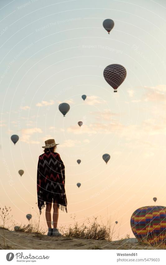Young woman and hot air balloons in the evening, Goreme, Cappadocia, Turkey Air Vehicle Air Vehicles aircrafts captive balloons fly stand light experience