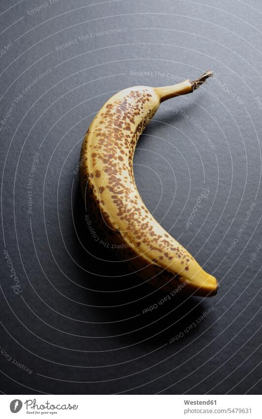 Dark stained banana on black background, close up single object 1 one healthy eating nutrition black backgrounds ripe ripeness coloured background