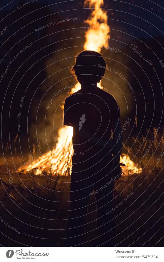 Boy standing in front camp fire at solstice motion moving Move awe awesomeness three-quarter length three quarter length rear view back view view from the back