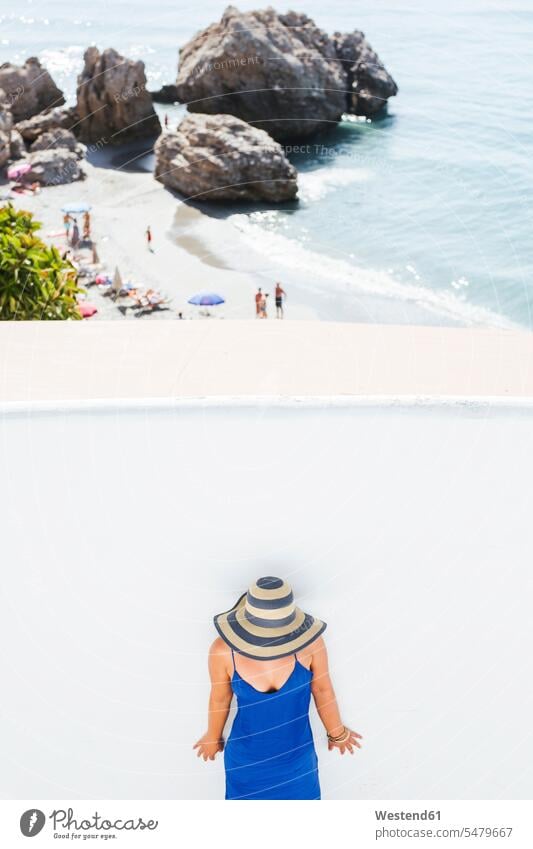 Woman wearing blue dress and straw hat standing in front of white wall, Nerja, Spain human human being human beings humans person persons caucasian appearance