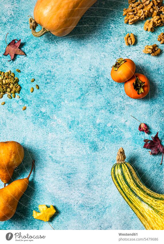 Autumnal background with pumpkins, fallen leaves, pears, walnuts, pumpkin seeds, persimmons and copy space studio shot studio photograph studio photographs