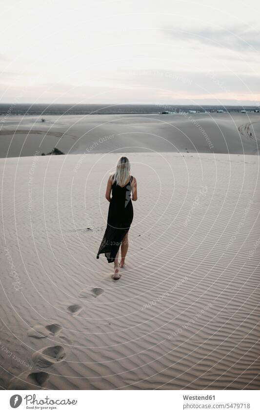 Back view of blond woman walking on sand dune, Algodones Dunes, Brawley, USA relax relaxing going colour colours country country side countryside experience