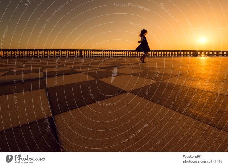 Italy, Livorno, silhouette of little girl dancing on Terrazza Mascagni at evening twilight females girls dance child children kid kids people persons