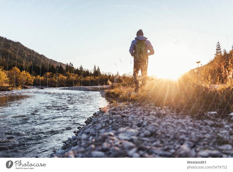 Male hiker with backpack walking on land by stream against clear sky at sunset color image colour image Austria leisure activity leisure activities free time