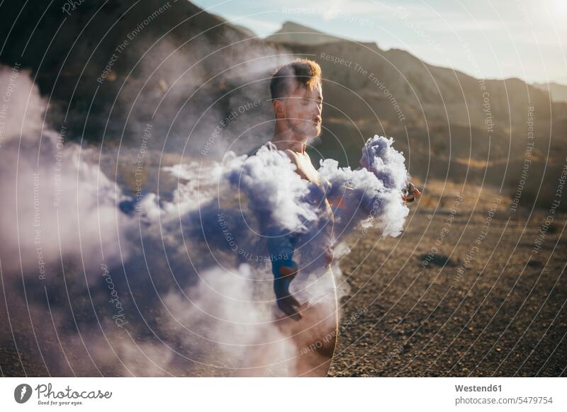 Naked man with smoke bomb standing at desert during sunny day color image colour image Spain leisure activity leisure activities free time leisure time outdoors