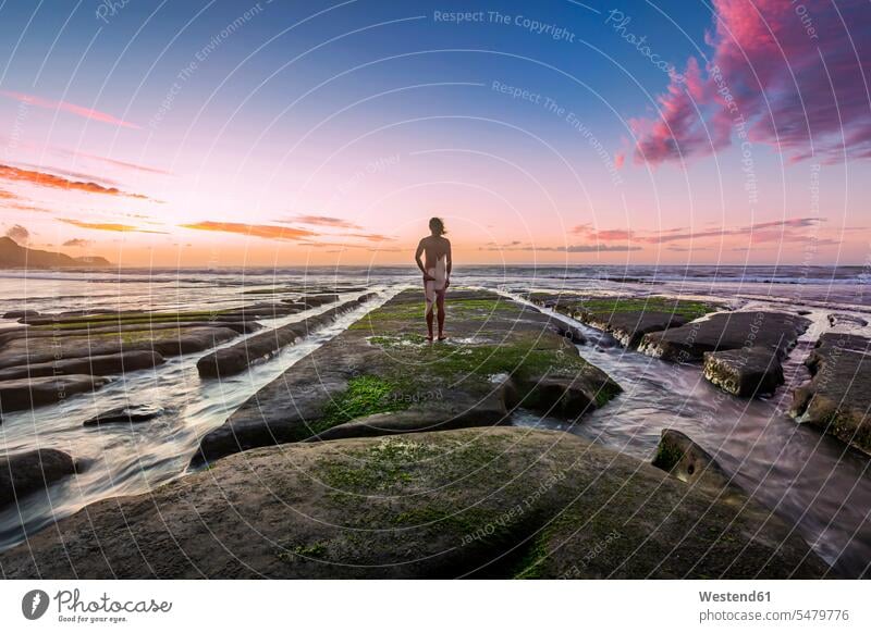 New Zealand, North Island, Rear view of naked man looking at ocean at sunset outdoors location shots outdoor shot outdoor shots sunsets sundown atmosphere