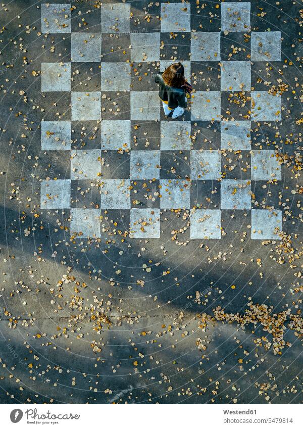 Woman standing on chessboard painted on asphalt color image colour image outdoors location shots outdoor shot outdoor shots day daylight shot daylight shots
