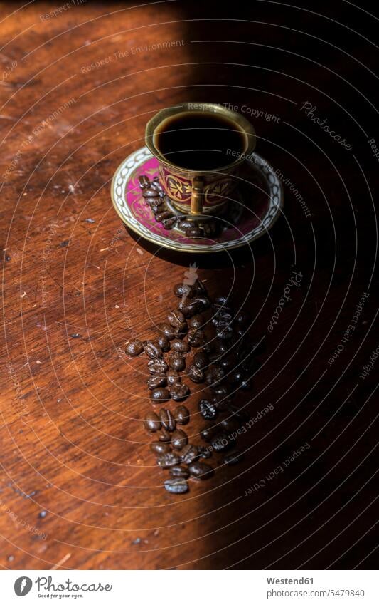 Cup of coffee and raw coffee beans lying on shaded table dark shadow shadows Shades Coffee Cup Coffee Cups Dishes Crockery Tableware Roasted Coffee Bean