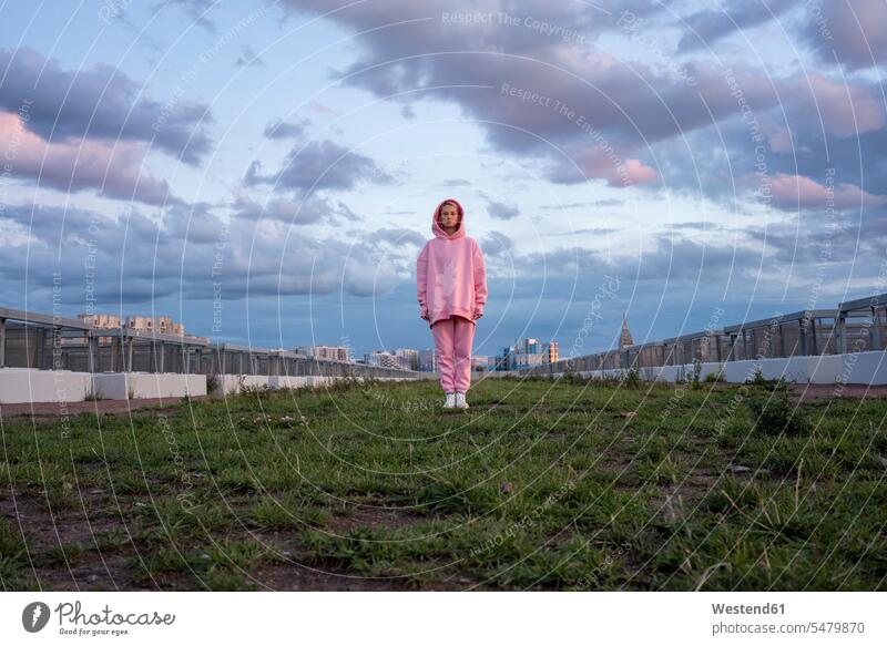 Portrait of young woman with pink hair wearing pink hooded shirt standing on grass outdoors location shots outdoor shot outdoor shots hooded top Hooded Shirt