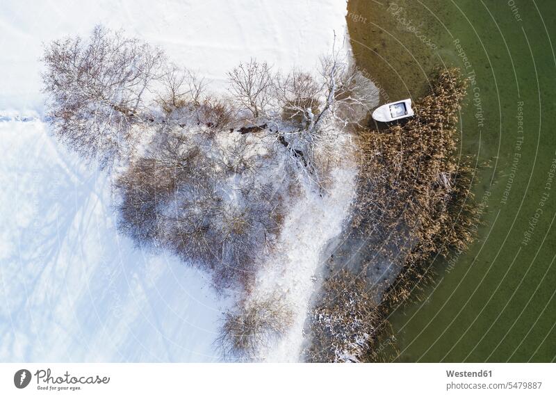 Boat moored at Irrsee by snow covered land during winter color image colour image outdoors location shots outdoor shot outdoor shots day daylight shot