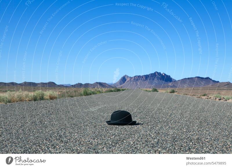 Morocco, Mecissi, Alnif, bowler hat lying on road mountain mountains concept concepts conceptual tarmac asphalt Blacktop vastness wide Broad Far copy space