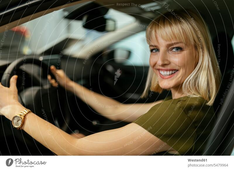 Blond woman choosing new car in car dealership female customer automobile Auto cars motorcars Automobiles select choose selecting car dealerships buying blond