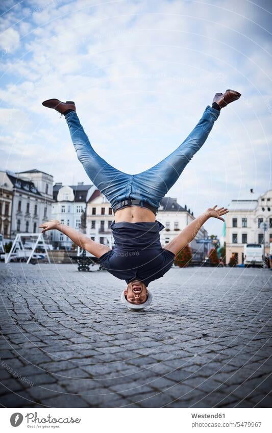 Man having fun doing headstand on square in the city headstands happiness happy Fun funny man men males Adults grown-ups grownups adult people persons