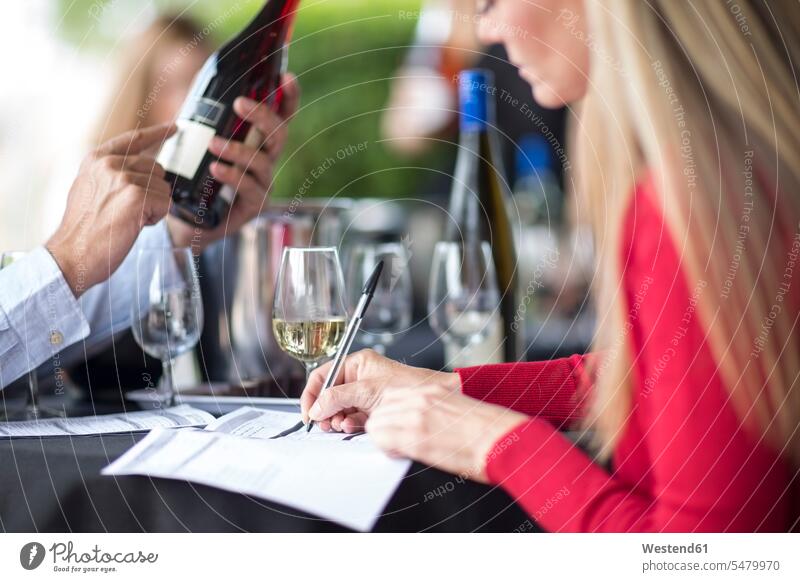 Man and woman tasting wine and taking notes Wine making a note note taking scrutiny scrutinizing restaurant restaurants Alcohol alcoholic beverage