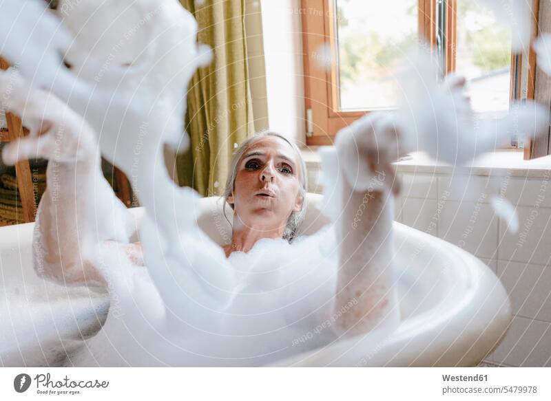 Portrait of woman in bathtub playing with foam foaming foamy females women portrait portraits tubs bathtubs bath tubs Adults grown-ups grownups adult people
