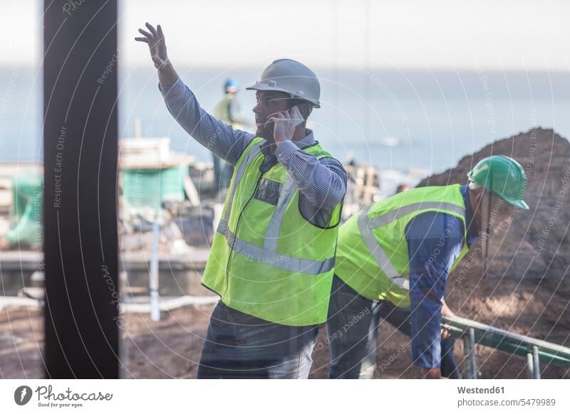 Men with reflective vests on construction site Building Site sites Building Sites construction sites mobile phone mobiles mobile phones Cellphone cell phone