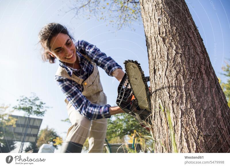 Woman on farm cuttiing tree with chain saw Plant Nursery nursery vegetable garden kitchen gardens Tree Trees lumbering fell felling Chainsaw Chain Saw chainsaws