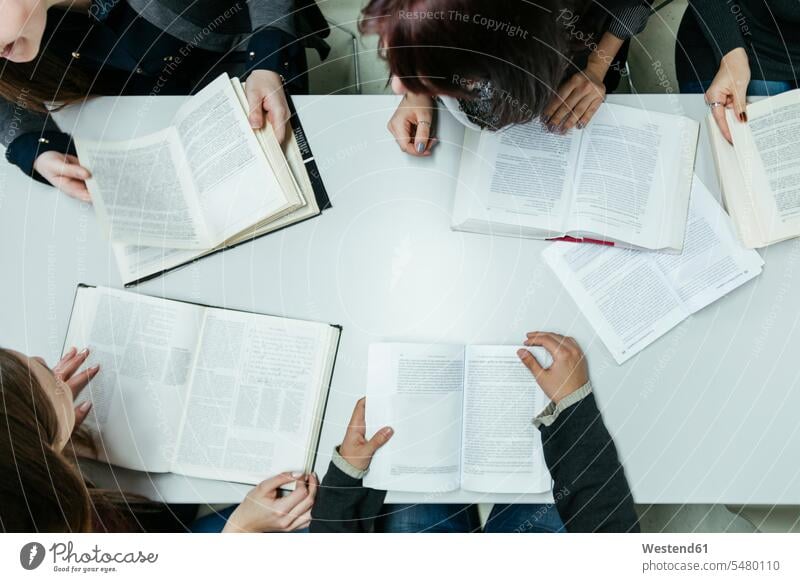 Group of students learning together in a library book books female students building buildings built structure built structures higher education discussing