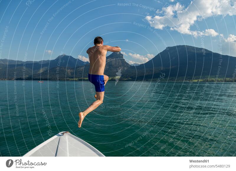 Austria, Sankt Wolfgang, man jumping from boat into lake men males water Leaping lakes Adults grown-ups grownups adult people persons human being humans