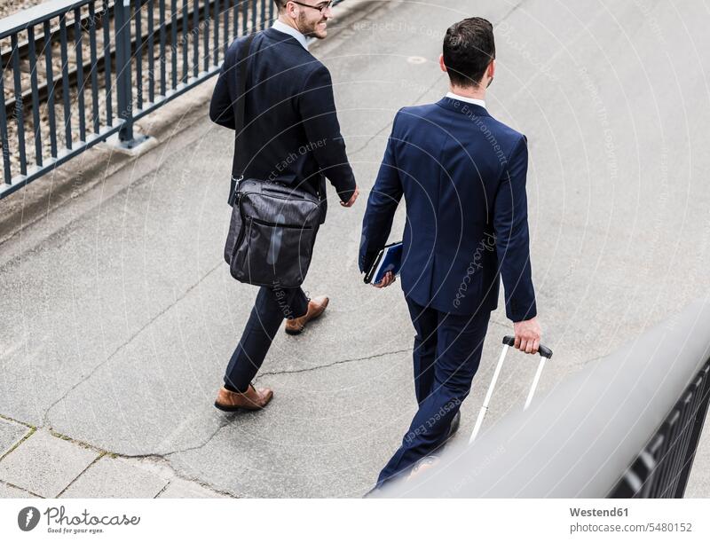 Businessmen on business trip walking with wheeled luggage suitcase suitcases going Business Trip executive travel Business Trips Business Travel