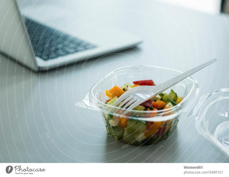 Plastic bowl with salad on desk in office plastic bowl plastic bowls business business world business life plastic fork plastic forks close-up close up closeups