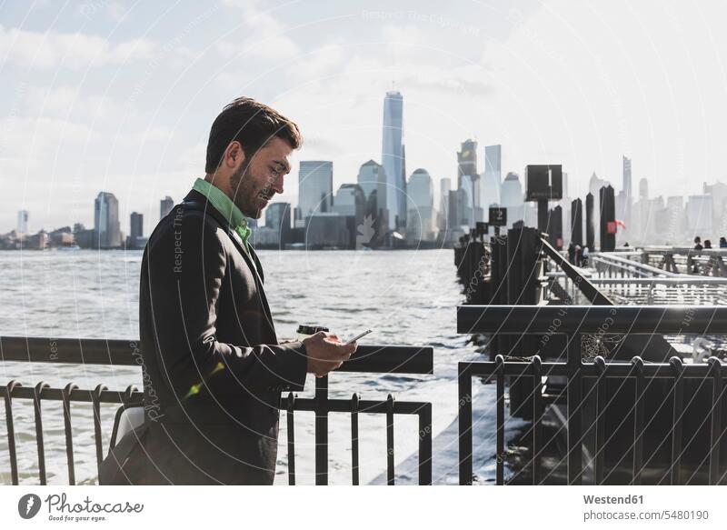 USA, businessman using cell phone at New Jersey waterfront with view to Manhattan Businessman Business man Businessmen Business men mobile phone mobiles