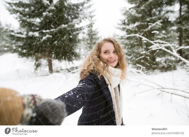 Portrait of happy young woman holding hand in winter forest females women winter landscape winter landscapes portrait portraits Adults grown-ups grownups adult