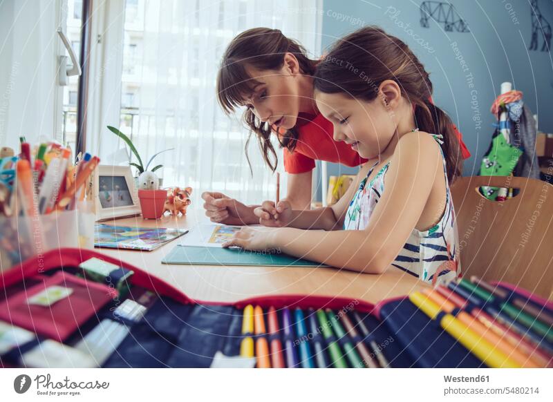 Mother helping girl doing her schoolwork at home learning daughter daughters mother mommy mothers ma mummy mama homework Home work child children family