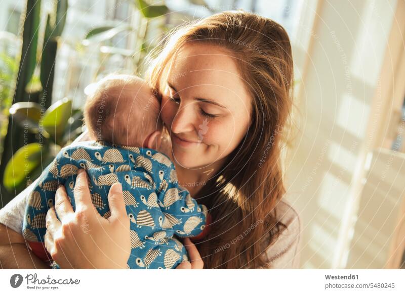 Mother holding her newborn baby boy at home infants nurselings babies smiling smile mother mommy mothers ma mummy mama people persons human being humans