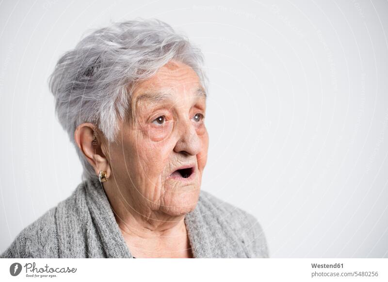 Portrait of surprised senior woman in front of white background Facial Expression Mimic amazement amazed looking sideways sideways glance Sideway Glance