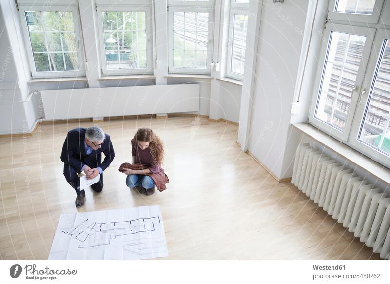 Real estate agent showing construction plan to client in empty apartment flats apartments explaining moving in move in real estate agent realtor talking