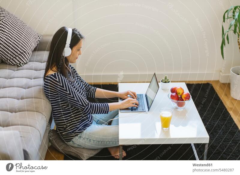 Young woman using laptop and headphones at home females women Laptop Computers laptops notebook Adults grown-ups grownups adult people persons human being