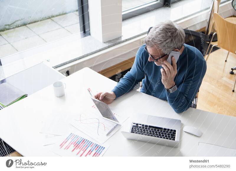 Mature man working in office with smart phone and digital tablet caucasian caucasian ethnicity caucasian appearance european sitting Seated wireless
