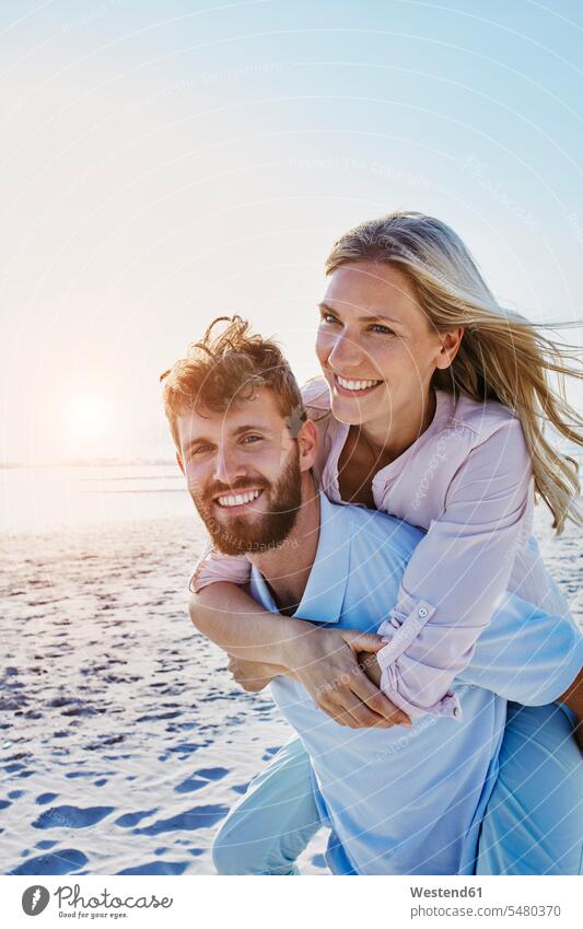 Portrait of happy couple on the beach smiling smile happiness piggyback piggy-back pickaback Piggybacking Piggy Back beaches twosomes partnership couples people