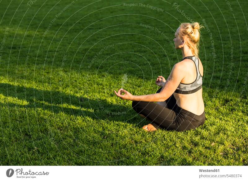 Woman doing yoga in park exercise exercises parks sitting Seated woman females women mindfulness aware awareness self-care relaxation exercise relaxed relaxing