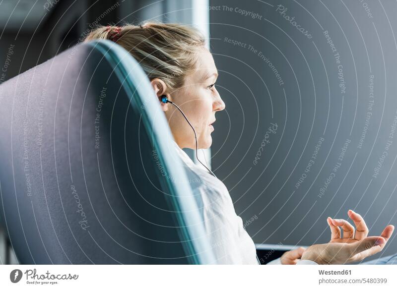 Woman sitting on couch with earphones businesswoman businesswomen business woman business women ear phone ear phones business people businesspeople