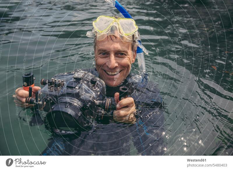 Portrait of happy man with underwater DSLR camera case in a lake cameras laughing Laughter diver divers men males diving positive Emotion Feeling Feelings