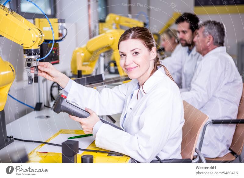 Portrait of smiling engineer examining industrial robot engineers Robot smile factory factories technology technologies engineering industry occupation