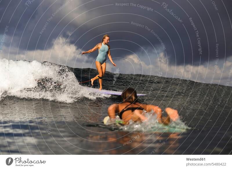 Indonesia, Bali, two women surfing wave waves surf ride surf riding Surfboarding Sea ocean woman females water water sports Water Sport aquatics Adults