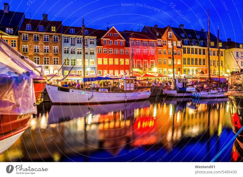 Denmark, Copenhagen, view of historic boats and row of houses at Nyhavn in the evening moored anchor anchored anchoring city view city pictures city views urban