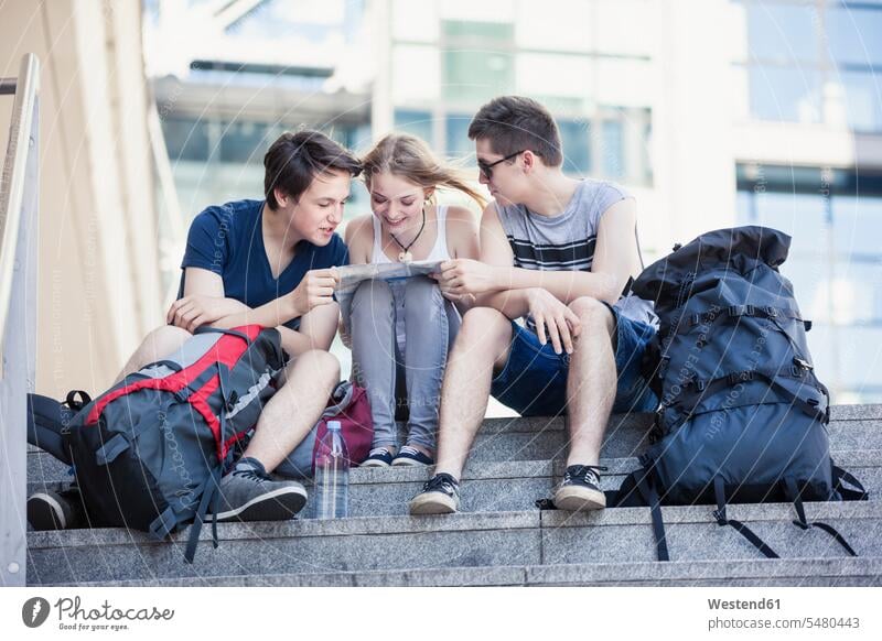 Young people exploring Berlin, looking at map Traveller Travellers Travelers visiting viewing backpacker Backpackers city map city maps Teenager Teens sitting