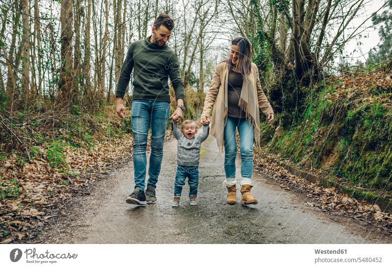 Pregnant woman walking with family in forest in autumn pregnant Pregnant Woman woods forests going families happiness happy people persons human being humans