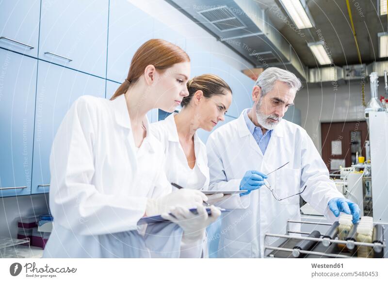 Three scientists in lab examining samples checking examine laboratory science sciences scientific swatch Swatches Samples examination examinations workplace
