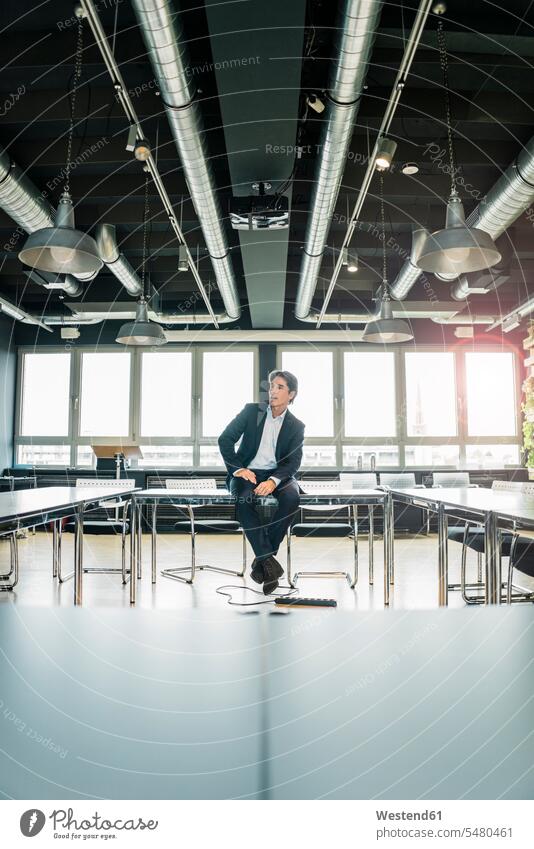 Businessman sitting on table in conference room Table Tables Seated Business man Businessmen Business men meeting room conference rooms meeting rooms office