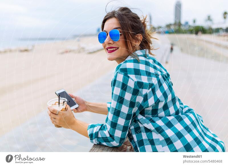 Young woman at the beach with cup of coffee and smart phone mobile phone mobiles mobile phones Cellphone cell phone cell phones attractive beautiful pretty