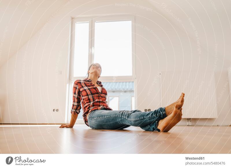 Mature woman moving house, sitting on floor, thinking females women flat flats apartment apartments ground land owner owners property move Moving Home floors